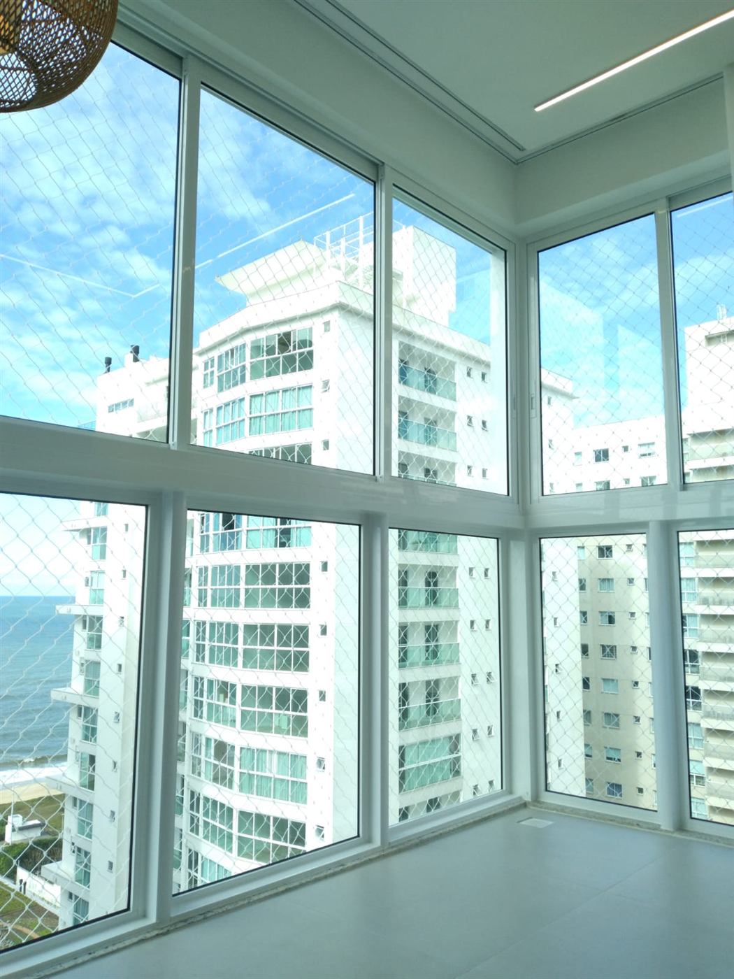 Envidraçamento de sacada com vista para o mar e prédios altos